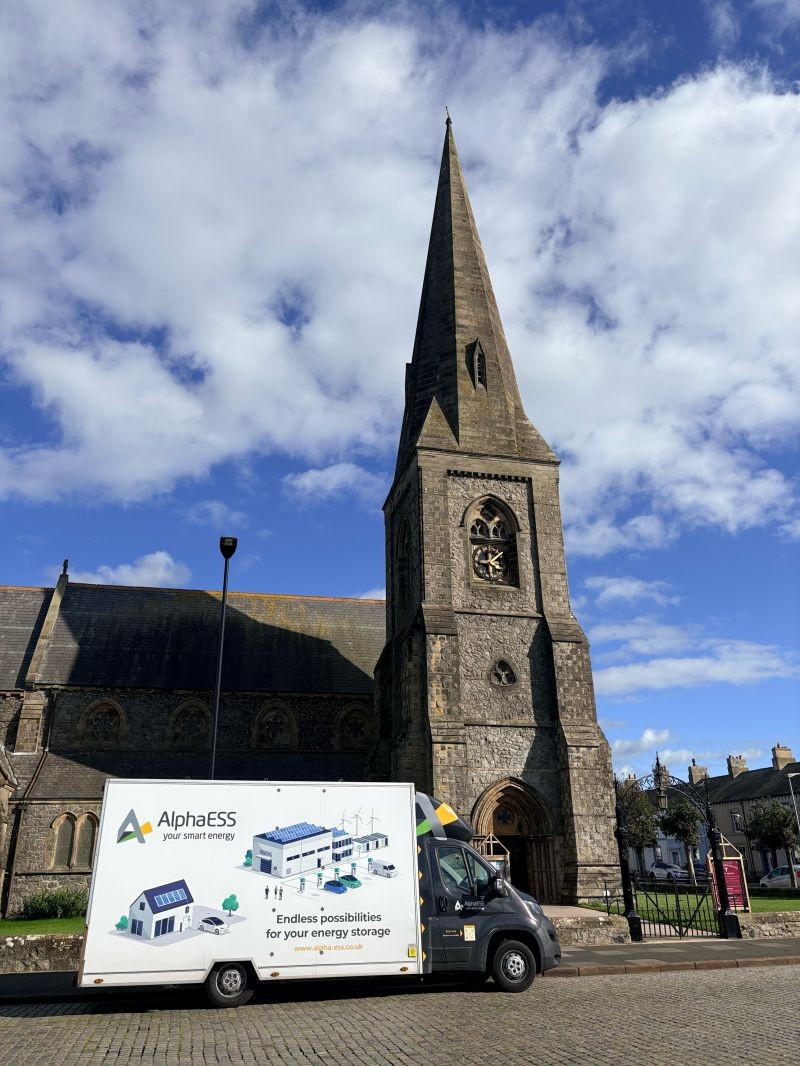 BESSIE, the AlphaESS UK mobile showroom, parked beside a village church on tour